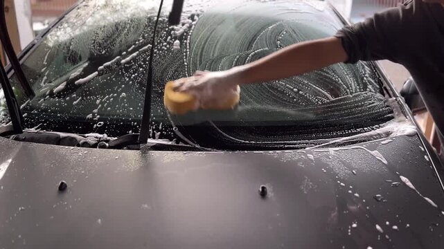 Wash the car by using a sponge to scrub the windshield.