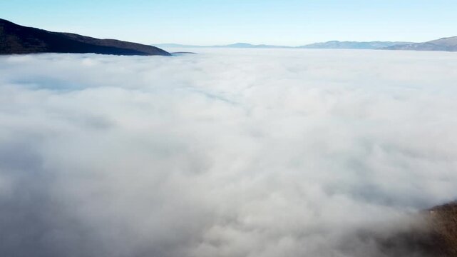 Fog and clouds covering the valley, drone footage. Air pollution trapped under cloud inversion. Flight above the clouds. 