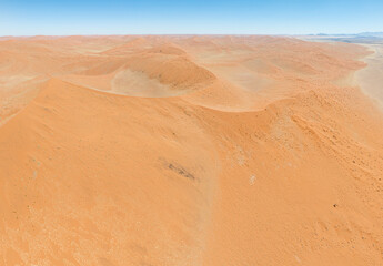 This high-quality drone photograph presents a sweeping aerial round flight over the dramatic landscapes of Namibia, offering a breathtaking bird’s-eye view of one of the world’s oldest deserts. The ca