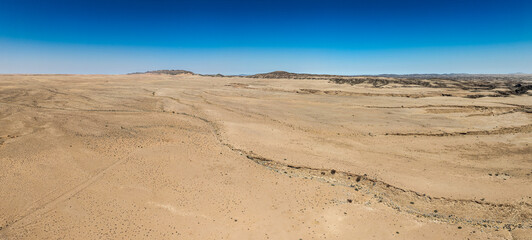 This high-quality drone photograph presents a sweeping aerial round flight over the dramatic landscapes of Namibia, offering a breathtaking bird’s-eye view of one of the world’s oldest deserts. The ca