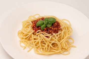 Macro photo of pasta with sauce and basil on a white plate