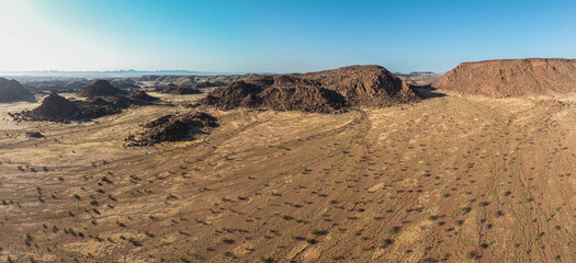 This high-quality drone photograph presents a sweeping aerial round flight over the dramatic landscapes of Namibia, offering a breathtaking bird’s-eye view of one of the world’s oldest deserts. The ca