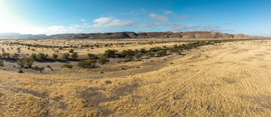 This high-quality drone photograph presents a sweeping aerial round flight over the dramatic landscapes of Namibia, offering a breathtaking bird’s-eye view of one of the world’s oldest deserts.