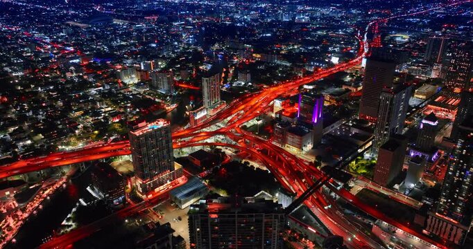 Stunning interchange illuminated red at night crossing the scenery of big city. Aerial perspective on the lively vibrant metropolis.