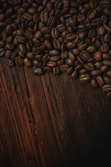Roasted coffee beans filling the upper section of a dark wooden table, creating a textured background with space