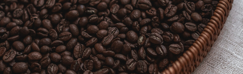 Roasted coffee beans creating a rich texture in a brown wicker basket, ready for brewing a fresh beverage