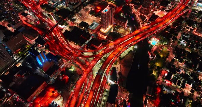 Lively multi-level interchange illuminated red at night. Hundreds of cars run by the highways in Miami, Florida, USA. Top view.