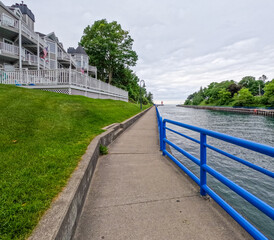 The scenic boardwalk along the Pine River Channel in Charlevoix, Michigan, USA. The channel connects Lake Charlevoix to Lake Michigan with plentiful boat traffic. Distant view of South Pier Lighthouse