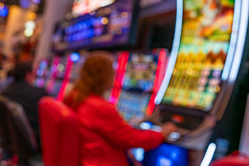 Fototapeta premium Abstract blurred casino scene with slot machines, neon lights and silhouettes creating vibrant gambling entertainment atmosphere indoors.