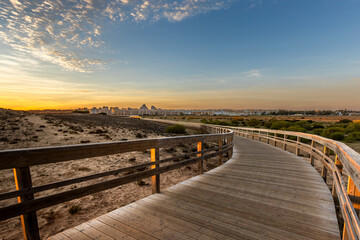 Fototapeta premium Wooden Boardwalk Through Coastal Dunes at Sunset, Armação de Pêra, Algarve
