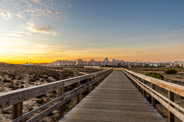 Obraz premium Wooden Boardwalk Through Coastal Dunes at Sunset, Armação de Pêra, Algarve