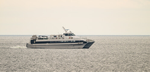 High speed passenger ferry cruising across calm open sea on overcast day.