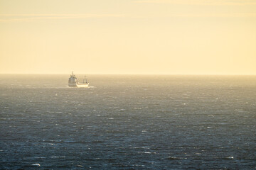 cargo ship sailing across vast open sea in moody evening light.