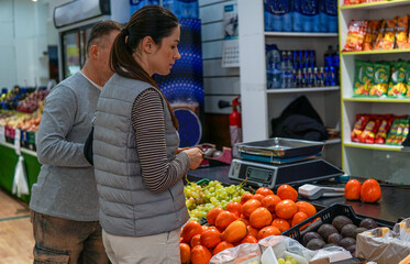 middle-aged man and woman buying fruits and vegetables at an outdoor market