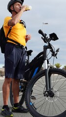 Mature man, 54 years old, enjoying a healthy lifestyle and wellbeing, hydrating with a drink bottle next to his electric mountain bike on a spring day in Canary Islands