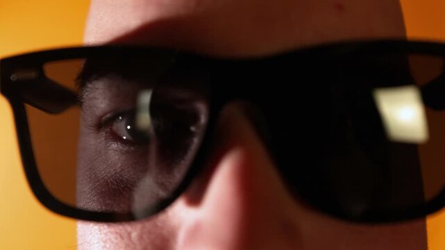 Extreme close-up of a man wearing sunglasses as the camera slowly zooms in, ending in an abstract dark blur.