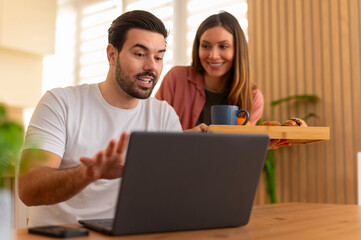 Couple video calling laptop while enjoying breakfast