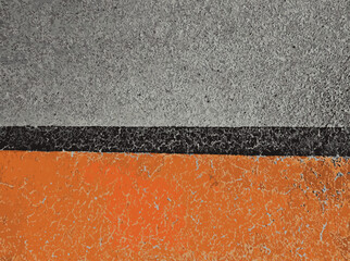 Abstract asphalt surface with orange, black and gray painted stripes, textured road marking background, urban pavement detail with color contrast, minimal composition and copy space.