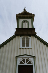 Architectural detail of a traditional wooden Icelandic church with green trim and steeple. Captured from below