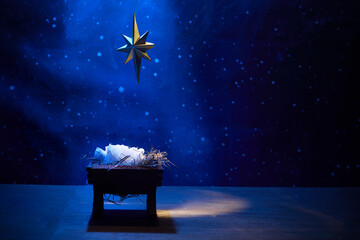 Obraz premium Starry Night Nativity. A nativity scene under a glowing star in a deep blue, starry background