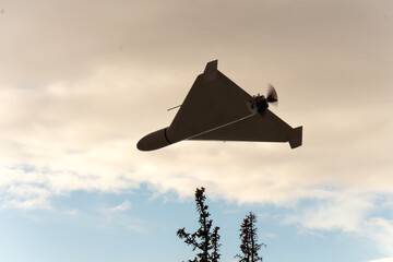 A military drone with a propeller is moving in the evening sky.