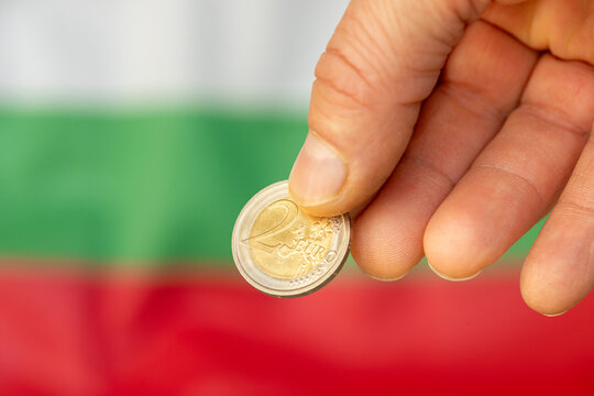 Bulgaria , money, entering the Eurozone. Symbol of the common currency of the European Union. 2 euro coin in fingers. Flag of Bulgaria. Business background. Financial concept. Close up