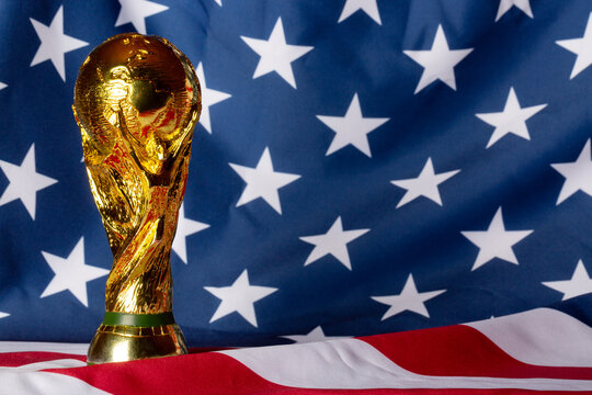 Moscow, Russia - December 13, 2025: FIFA World Cup Trophy against Unites States of America national Flag. USA is the FIFA World Cup 2026 host country with Mexico and Canada