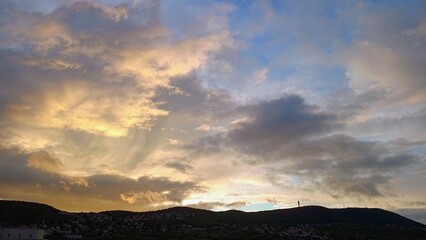 Beautiful sunset with yellow clouds in blue sky over the mountain