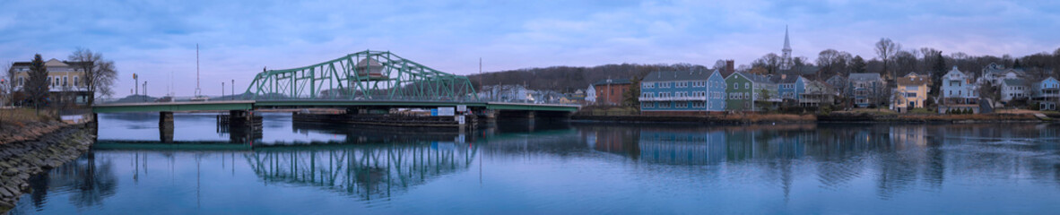 A New England winter landscape with the landmark Grand Avenue Swing Bridge and historic houses and church on the forest hill above the Quinnipiac River in Fair Haven, New Haven County, Connecticut