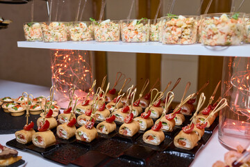 Elegant dining presentation, Sophisticated arrangement of canapes on stylish table setting, Exquisite black trays with gourmet delicacies showcased in upscale event ambiance