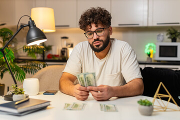 Arabian man at home counts dollar money cash uses calculator checks bills marks paid tracks saving....