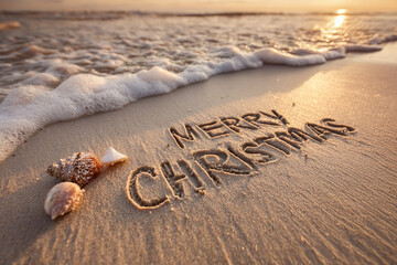 Merry Christmas Hand-Drawn Carved into Smooth Wet Sand with Golden Sunset Glow and Tiny Ornaments and Seashell Beside Text &ndash; ideal for seasonal promotions