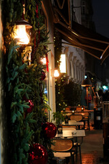 Restaurant tables and chairs outside on sidewalk and Christmas decorations around entrance on Calea Victoriei boulevard in Bucharest