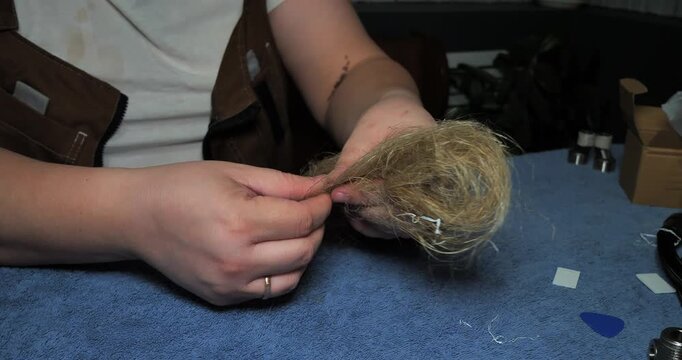 Close-up view of a professional plumber's hands skillfully preparing natural hemp fiber, or oakum, to create a reliable watertight seal for threaded pipe joints in a plumbing system.