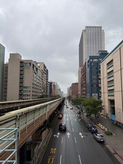 Obraz premium Taiwan City Street: View of a busy city street in Taiwan flanked by tall skyscrapers and modern architecture under a bright sky.
