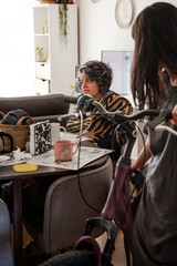 A woman is sitting at a table with a mug and a bicycle