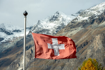 Swiss Flag Flies Against Fresh Snow On The Alps