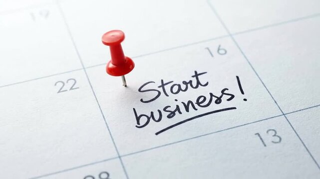 Red Pushpin on Calendar Marking 'Start business!' Message, Representing a New Venture, Entrepreneurial Planning, and Scheduled Launch Date