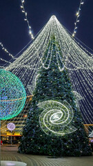 Large Christmas tree decorated with sparkling lights and ornaments in winter city square. Holiday background  Happy new year 2026