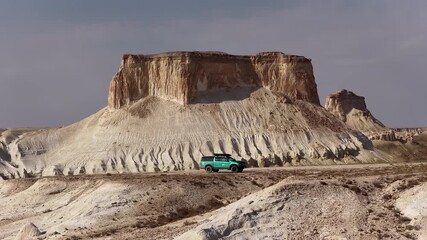 Pickup truck driving on a dirt road in a vast desert landscape of Bozjyra or Bozzhyra, Kazakhstan