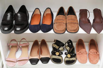 Different pairs of shoes on shelves indoors, closeup