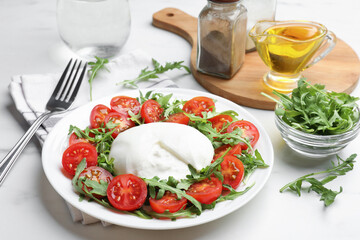 Delicious burrata cheese with arugula and tomatoes on light table, closeup