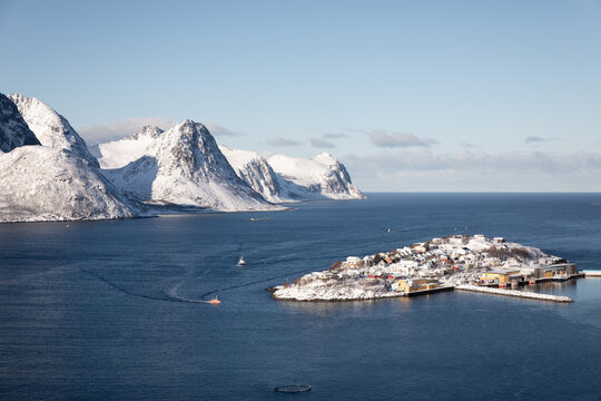 Husoy island, blue sea, and snowy mountains with two fishing boats