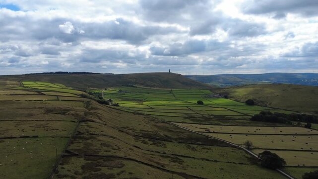 Aerial view of the landscape at Erringdon Grange near Hebden Bridge showing meadows with cows and sheep grazing and Stoodley Pike Moor and monument in the distance