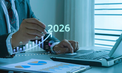 Businessman analyzing financial data with rising growth charts and digital forecast for 2026, illustrating business planning, investment strategy, and future market opportunities.
