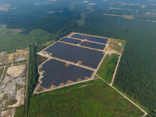 Aerial view of huge solar farm surrounded by palm oil plantation. Green renewable energy resources. Future of sustainable energy generation. Zero pollution concept.