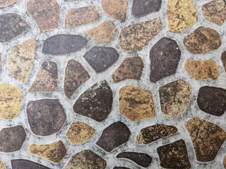 Natural stone pattern floor tile texture with rustic brown and grey pebbles. Abstract earthy background for interior design and architecture