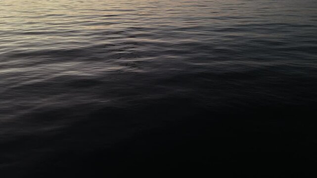 Close up drone view of dark undulating sea waves at twilight with subtle blue reflections portraying the power and mystery of the ocean in vertical format