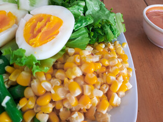 Healthy Cobb Salad Style Plate with Boiled Eggs, Corn, and Green Beans on a Wooden Table