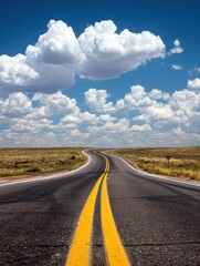 Fototapeta premium Winding Road Stretches Towards Horizon Under Blue Sky With Scattered Clouds on a Summer Day Along the Coastline